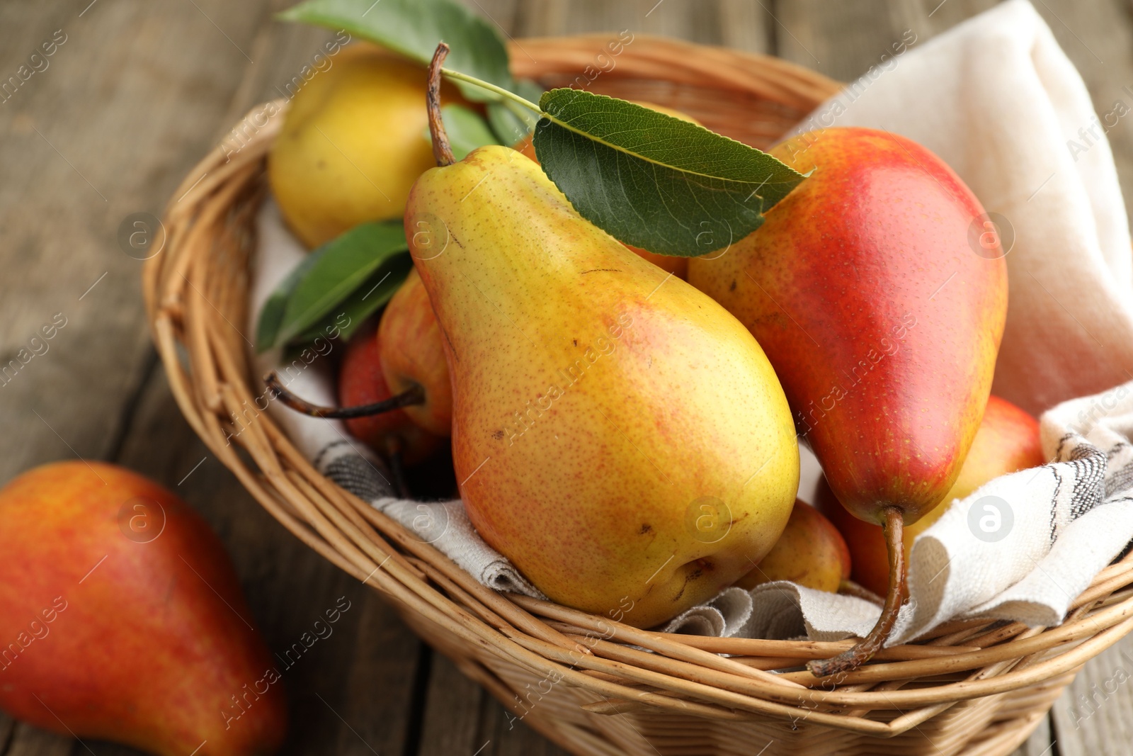 Photo of Ripe juicy pears in wicker basket on table, closeup