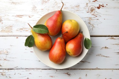 Photo of Ripe juicy pears in bowl on light wooden table, top view