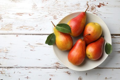 Photo of Ripe juicy pears in bowl on light wooden table, top view. Space for text