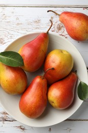 Photo of Ripe juicy pears in bowl on light wooden table, top view