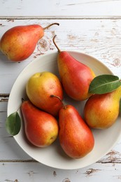 Photo of Ripe juicy pears in bowl on light wooden table, top view