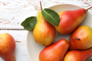 Photo of Ripe juicy pears in bowl on light wooden table, top view