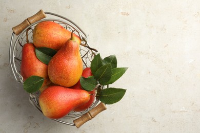 Photo of Ripe juicy pears in metal basket on grey textured table, top view. Space for text