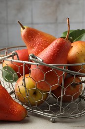 Photo of Ripe juicy pears in metal basket on grey textured table, closeup