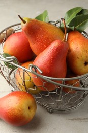 Photo of Ripe juicy pears in metal basket on grey textured table, closeup