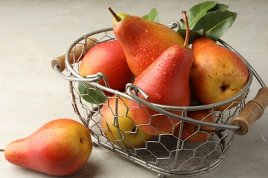 Photo of Ripe juicy pears in metal basket on grey textured table, closeup