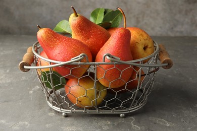 Photo of Ripe juicy pears in metal basket on grey textured table