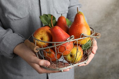 Photo of Woman holding metal basket with ripe juicy pears indoors, closeup