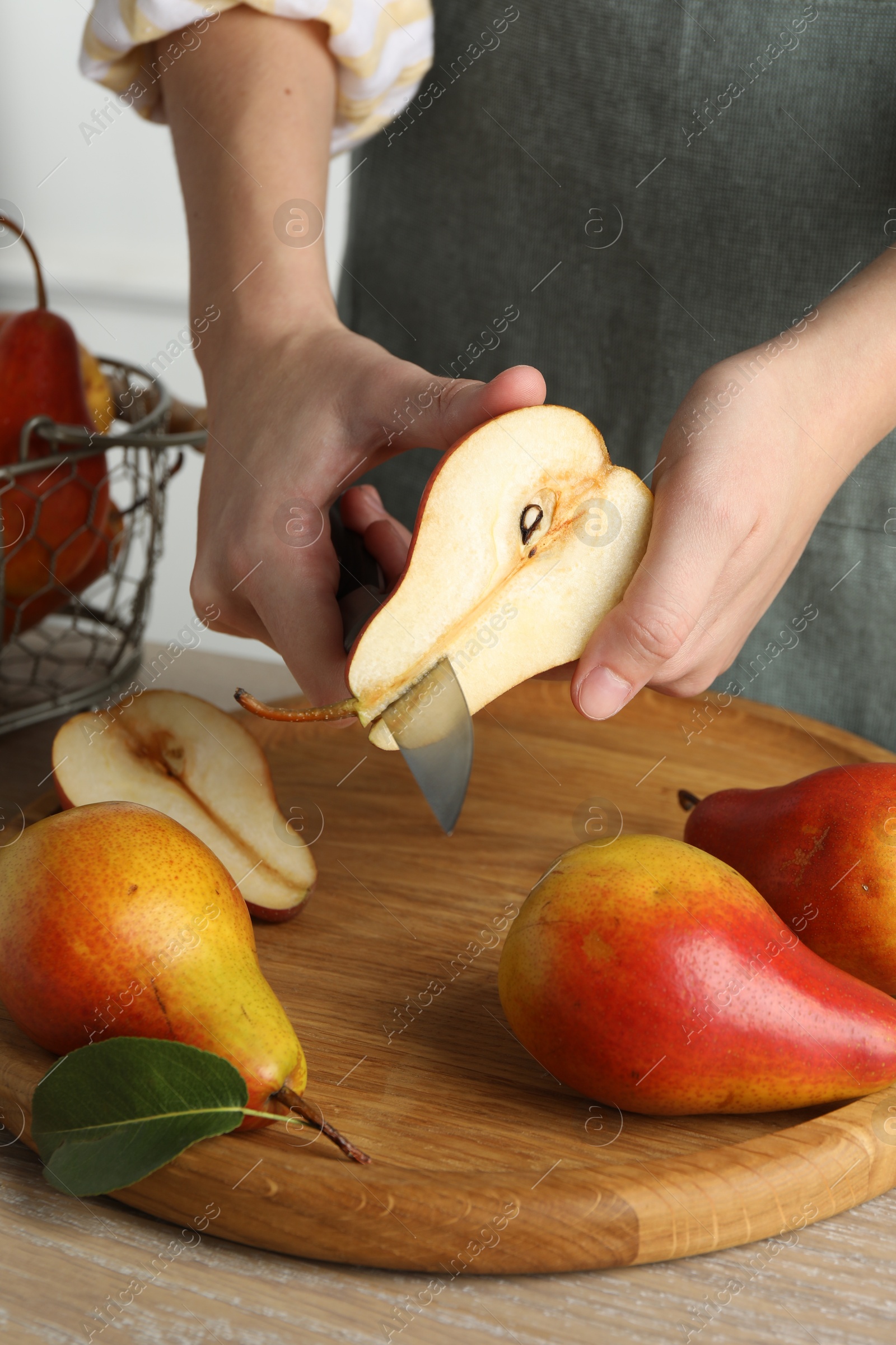 Photo of Woman cutting pear at wooden table, closeup