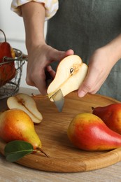 Photo of Woman cutting pear at wooden table, closeup