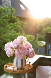 Beautiful pink peony flowers in vase on balcony railing outdoors