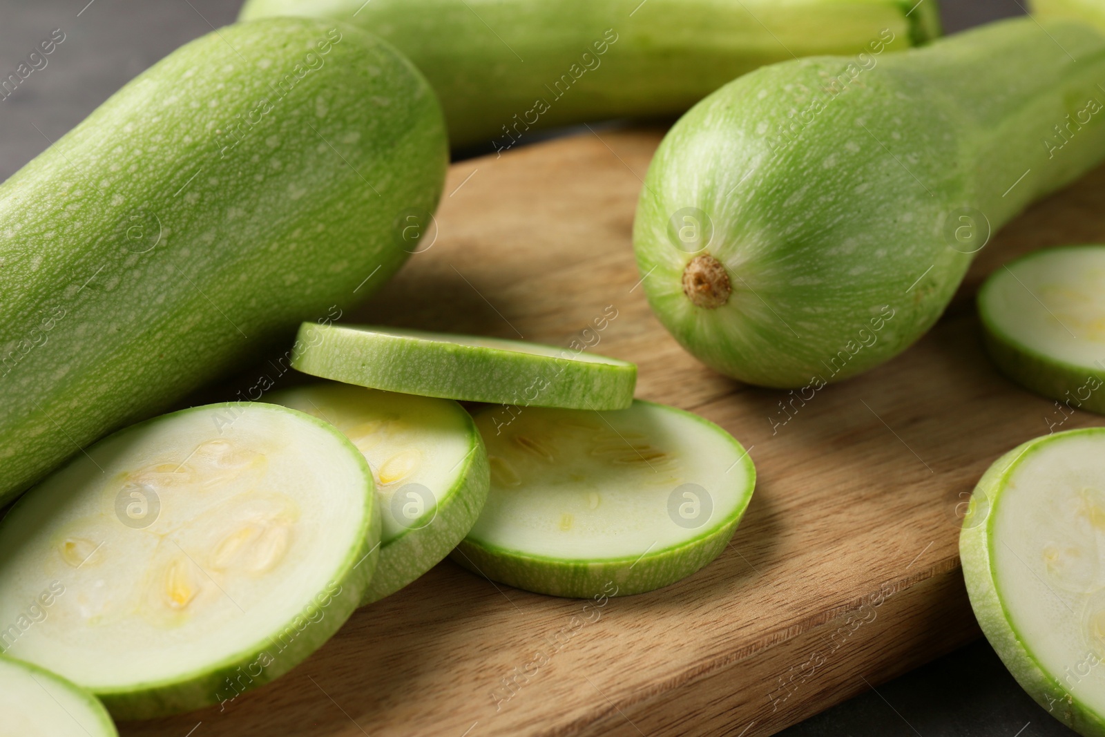 Photo of Board with fresh cut and whole zucchinis on table, closeup