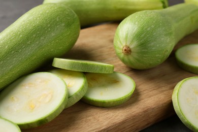 Photo of Board with fresh cut and whole zucchinis on table, closeup