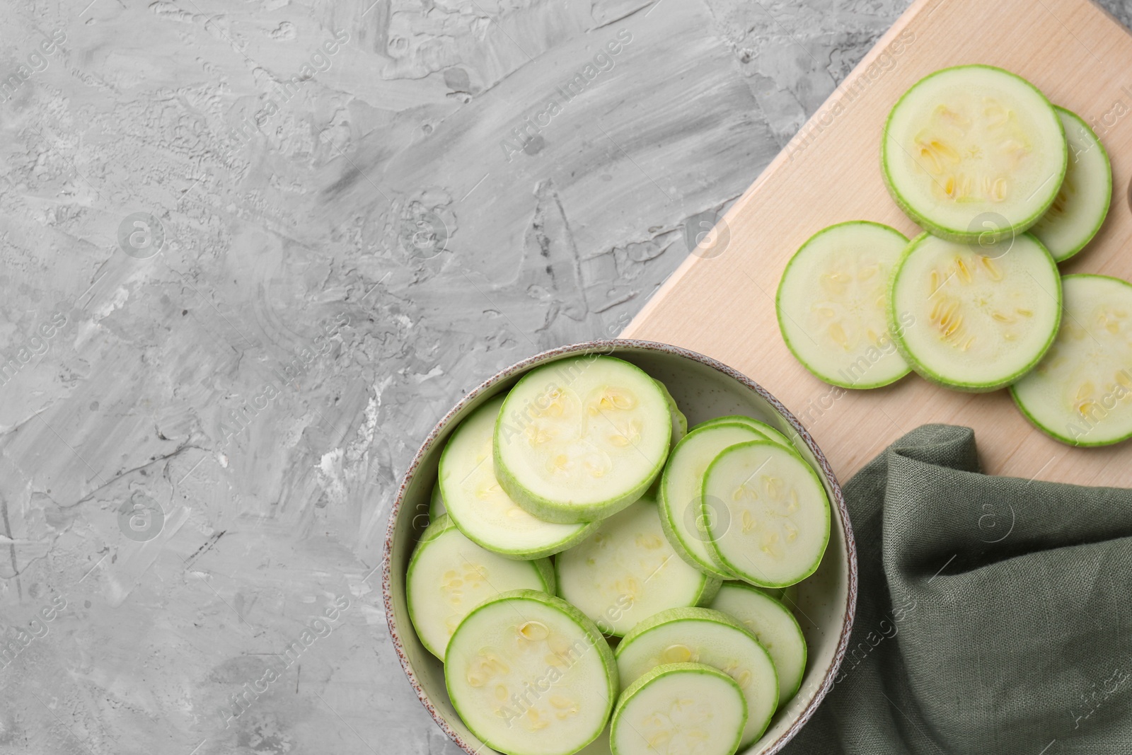 Photo of Fresh cut zucchinis on grey textured table, flat lay. Space for text