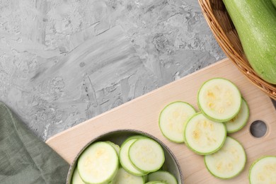 Photo of Fresh cut zucchinis on grey textured table, flat lay. Space for text