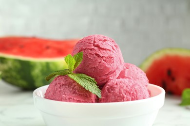 Scoops of tasty watermelon sorbet with mint in bowl on white table, closeup