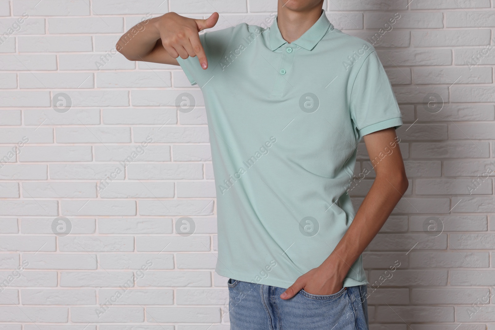 Photo of Teenage boy wearing light green t-shirt near white brick wall, closeup. Space for text