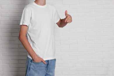 Teenage boy wearing t-shirt near white brick wall, closeup. Space for text