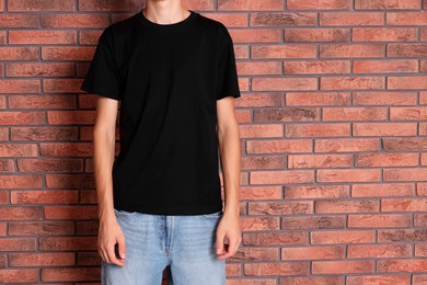 Photo of Teenage boy wearing black t-shirt near brick wall, closeup. Space for text