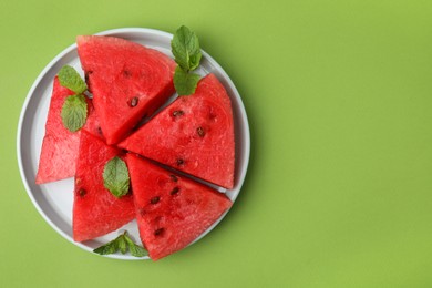 Photo of Pieces of tasty watermelon and mint on green table, top view. Space for text