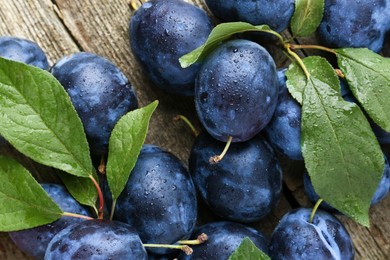 Photo of Tasty ripe plums and leaves on table, flat lay