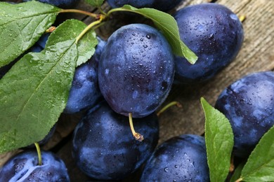 Photo of Tasty ripe plums and leaves on table, flat lay