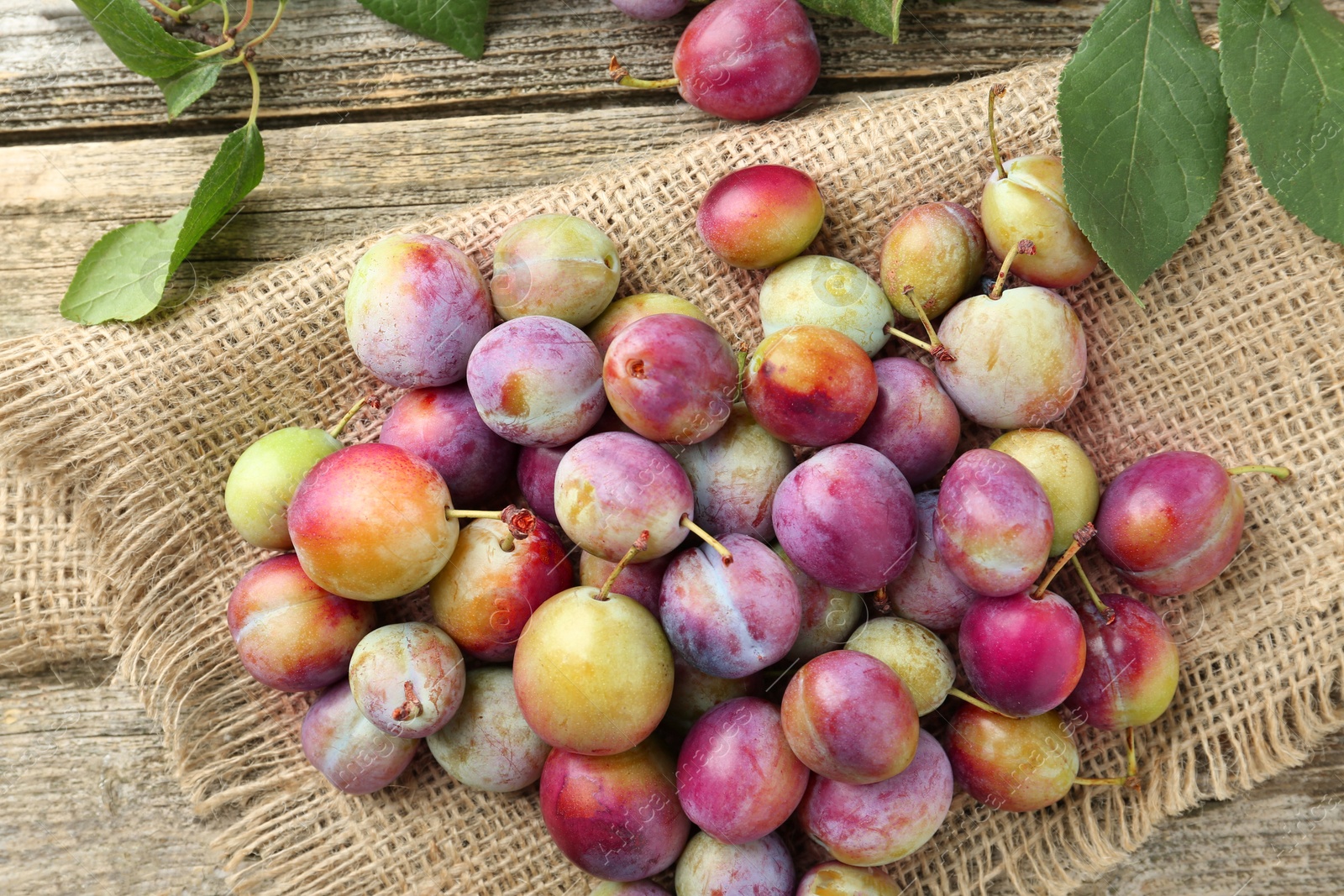 Photo of Tasty ripe plums on wooden table, flat lay