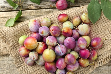 Photo of Tasty ripe plums on wooden table, flat lay