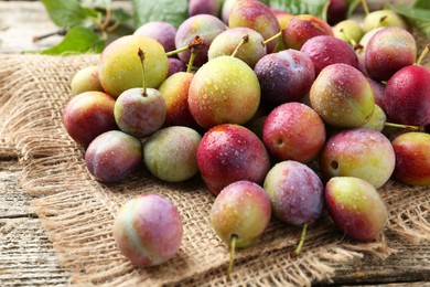 Photo of Pile of tasty ripe plums on wooden table, closeup