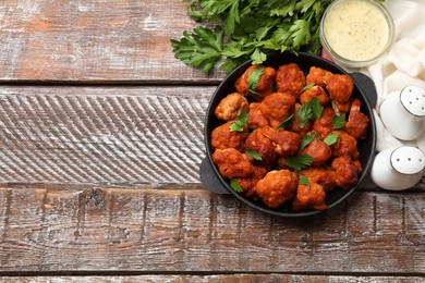 Photo of Baked cauliflower buffalo wings with parsley served on wooden table, flat lay. Space for text