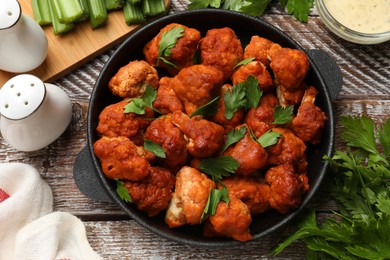 Photo of Baked cauliflower buffalo wings with parsley served on wooden table, flat lay