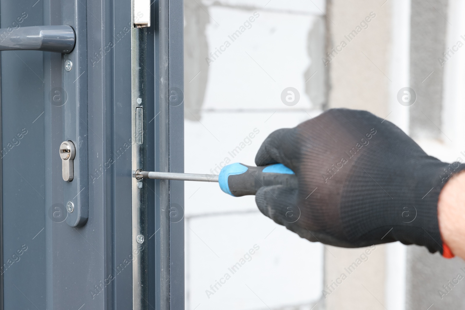 Photo of Repairman installing new door with screwdriver indoors, closeup