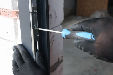 Photo of Repairman installing new door with screwdriver indoors, closeup