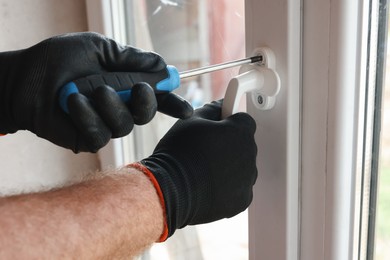 Photo of Repairman installing new window with screwdriver indoors, closeup