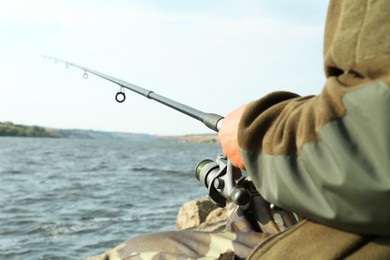 Fisherman with rod fishing near lake at summer, closeup