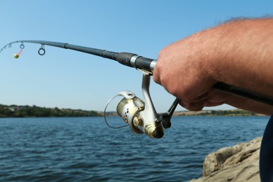 Photo of Fisherman with rod fishing near lake at summer, closeup