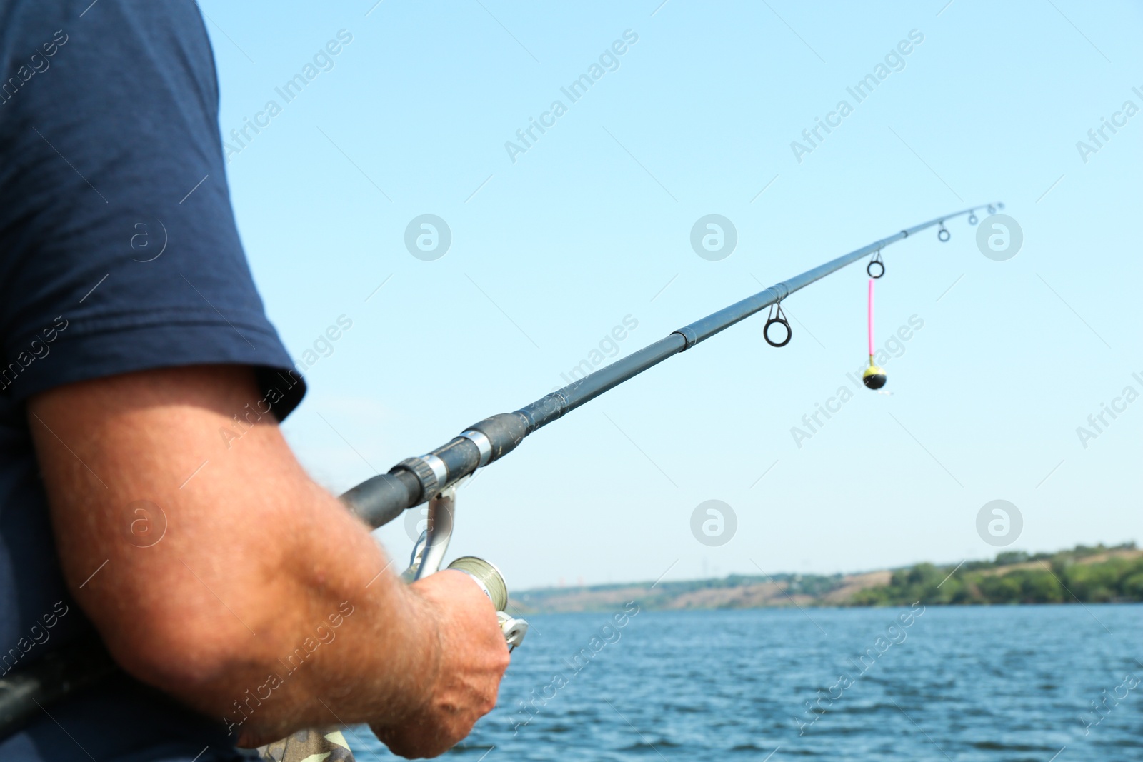 Photo of Fisherman with rod fishing near lake at summer, closeup