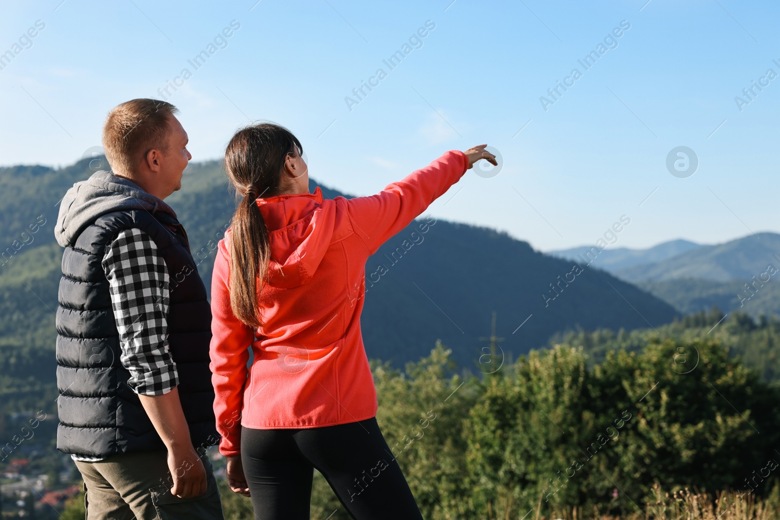 Photo of Couple in beautiful mountains, back view. Space for text