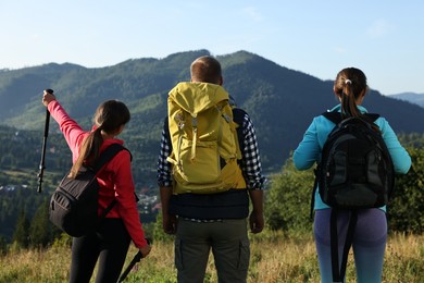 Photo of Friends with backpacks in beautiful mountains, back view