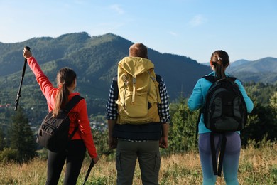 Photo of Friends with backpacks in beautiful mountains, back view