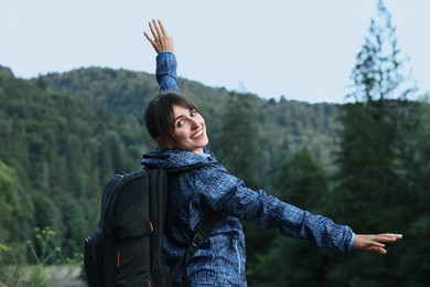 Smiling woman with backpack in beautiful mountains