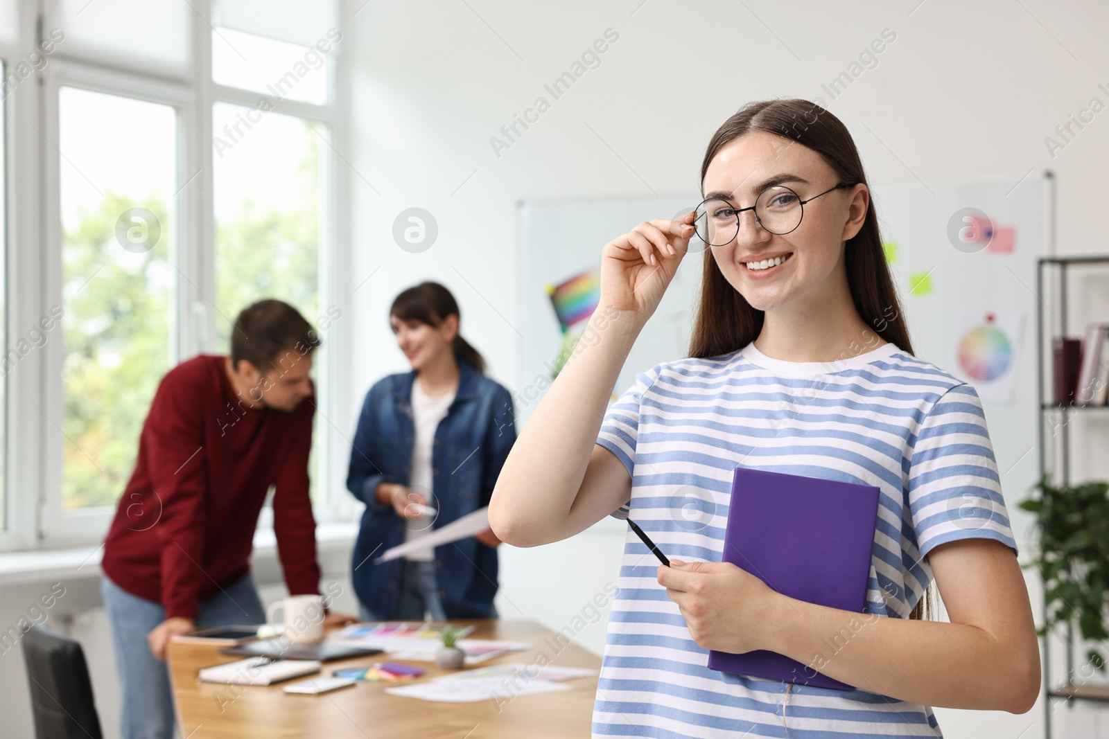 Photo of Portrait of happy young designer with notebook in office