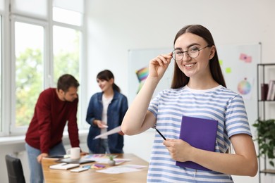 Photo of Portrait of happy young designer with notebook in office