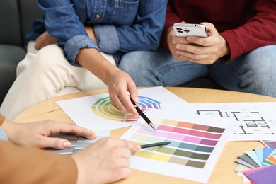 Photo of Designer discussing project with clients at table indoors, closeup