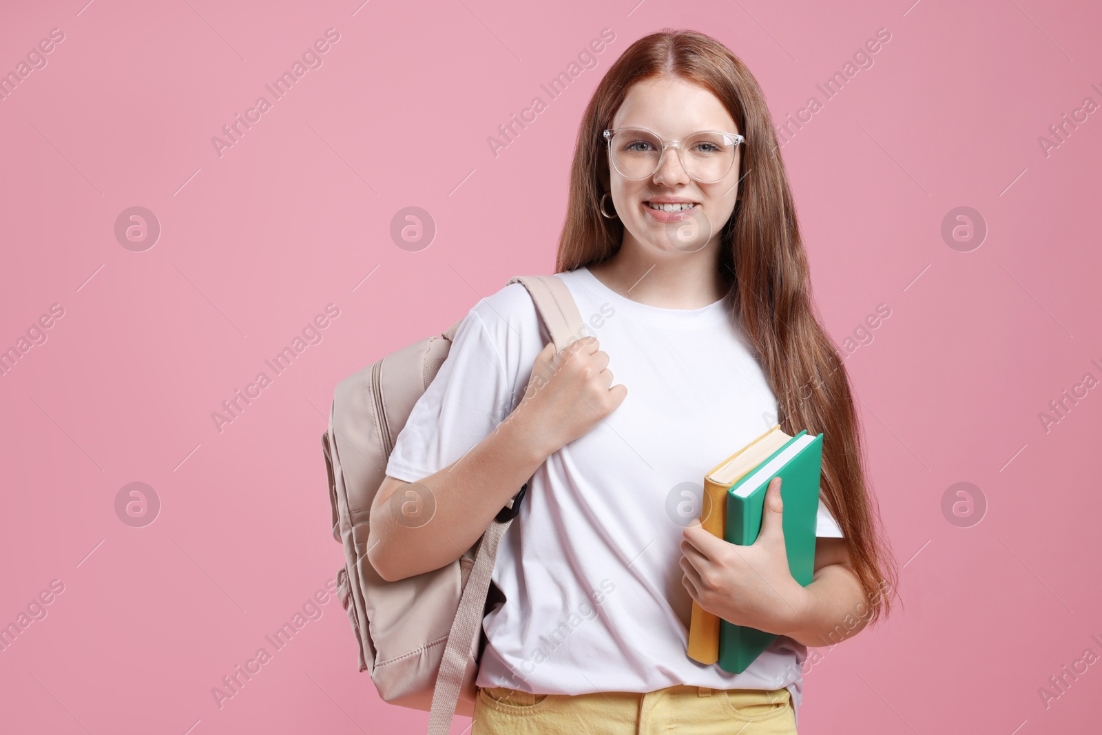 Photo of Teenage girl with backpack and books on pink background