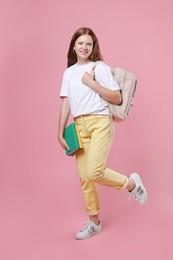 Photo of Teenage girl with backpack and books on pink background