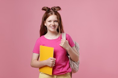 Photo of Teenage girl with backpack and notebook on pink background