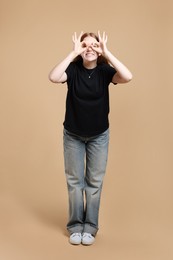 Photo of Cheerful teenage girl posing on beige background