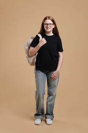 Photo of Teenage girl with backpack on beige background