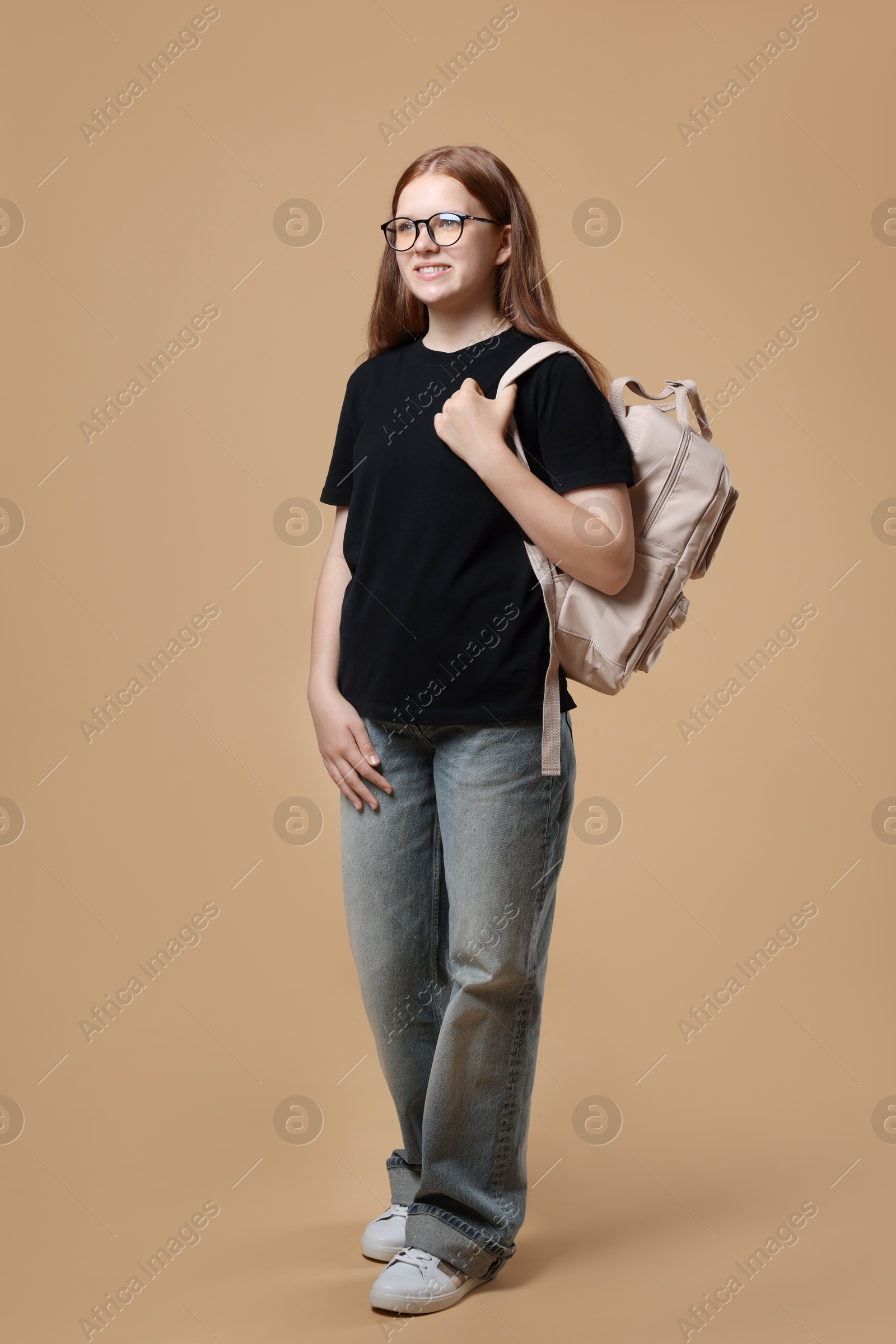 Photo of Teenage girl with backpack on beige background